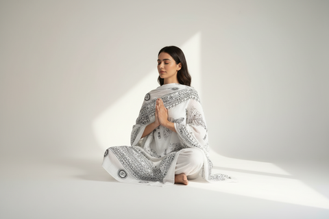 Woman wrapped in a white and black patterned shawl on a white background