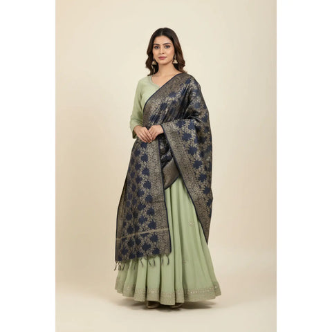Woman wearing a green traditional outfit with a dark floral shawl on a beige background